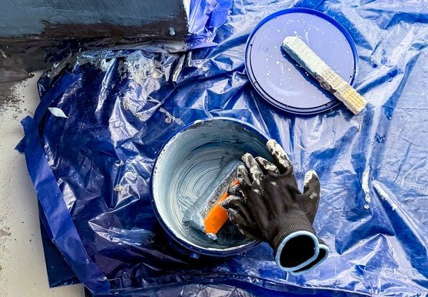 Freshly waterproofed bathroom floor with blue membrane and tiled walls during a renovation