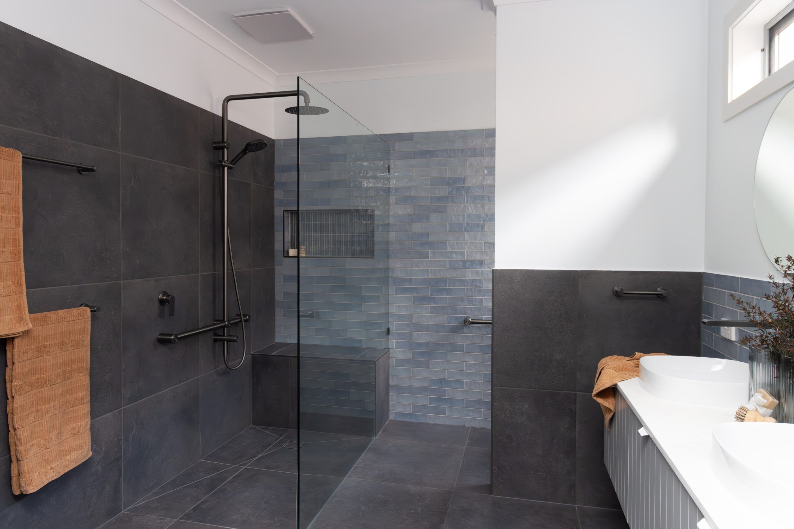 Frameless walk-in shower with blue tile feature wall and black tapware in a Now Bathrooms renovation"